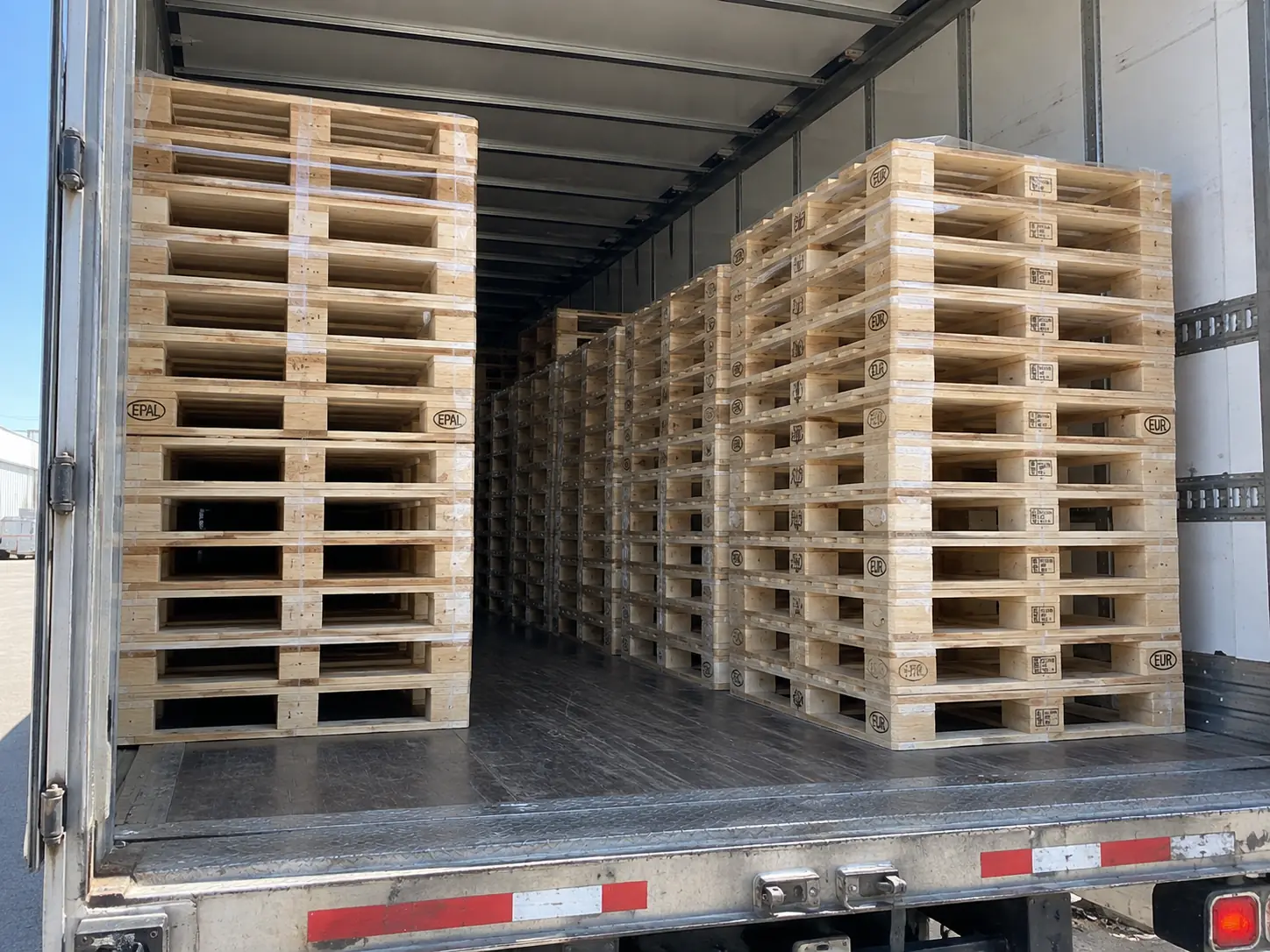 Looking into a loaded trailer stacked with new EPAL and EUR-stamped Euro block pallets, banded and strapped in rows.